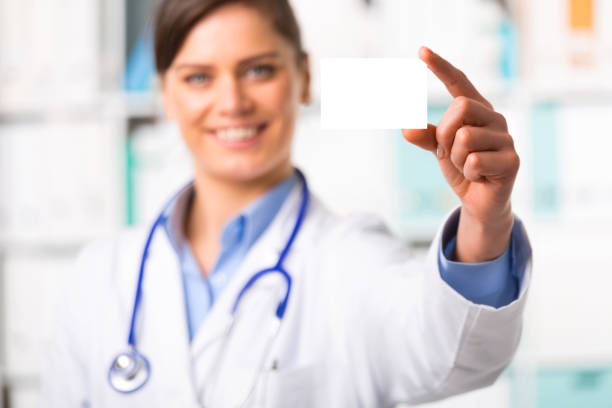 Young female doctor with blank business card stock photo