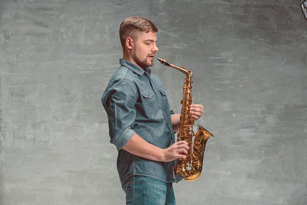 istock Happy saxophonist with sax over gray background 638763972
