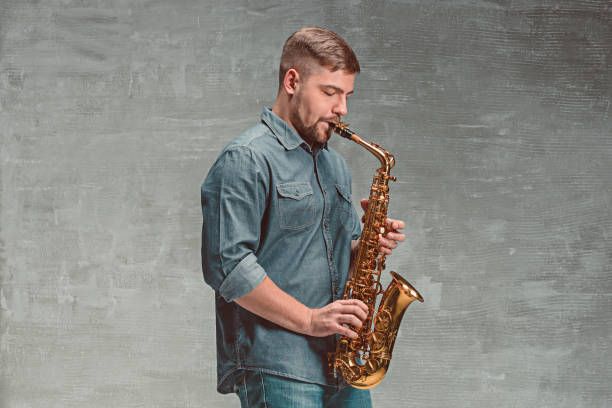 istock Happy saxophonist playing music on sax over gray background 638765096