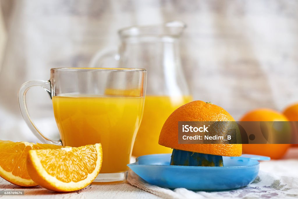 Glass of orange juice Plastic juicer with glass of fresh orange juice on white rustic wooden background. Copy space Orange Juice Stock Photo