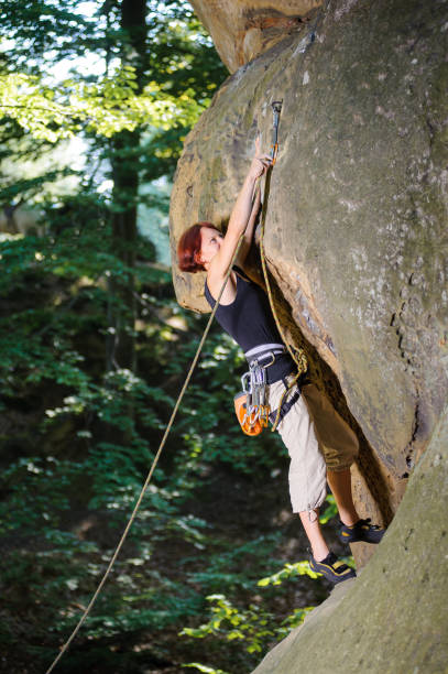 istock Female climber climbing with rope on a rocky wall 638770518