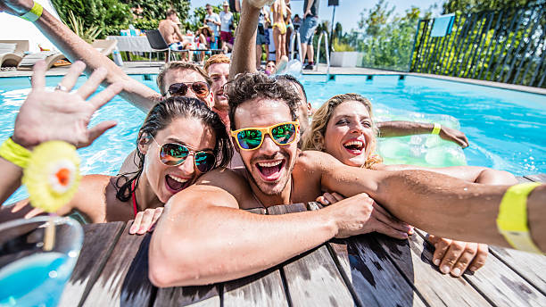 Young friends taking selfie Group of young friends taking selfie at pool side during pool party. pool party stock pictures, royalty-free photos & images