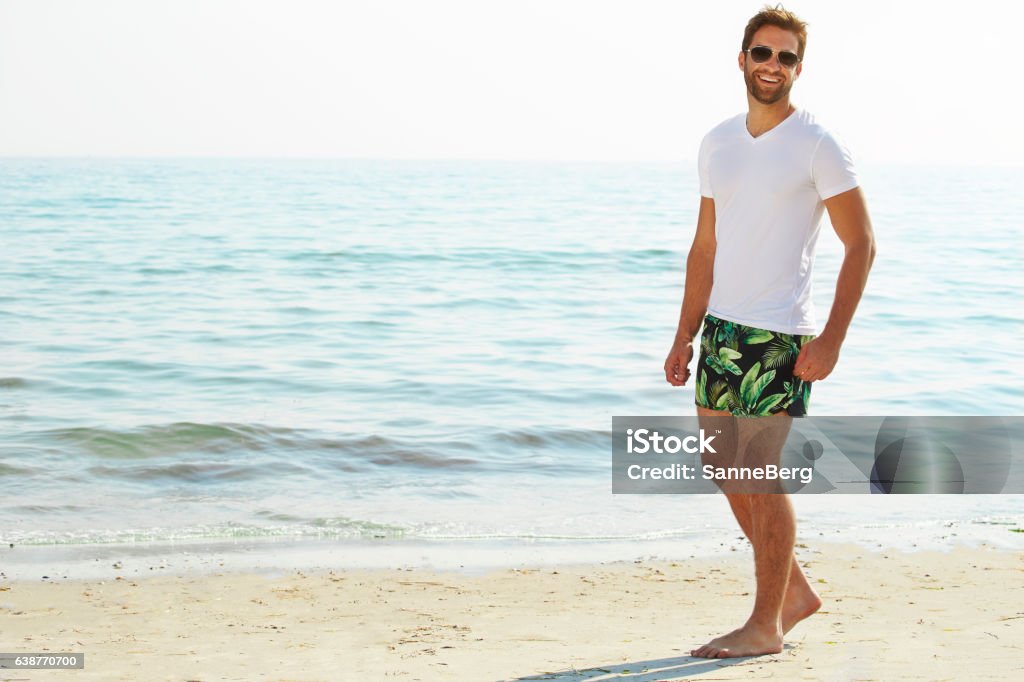 Shorts guy on beach Shorts guy on beach smiling at camera Men Stock Photo