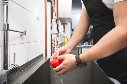 Close up on chef hand washing red pepper in sink