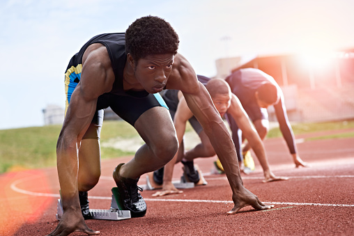 Shot of a group of runners crouching in starting blocks before a race on a running track