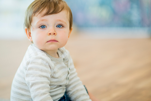 A young baby is looking directly at the camera.