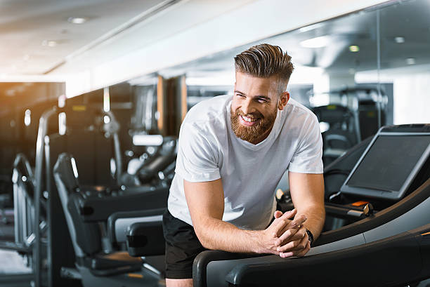 feliz hombre sonriente en el gimnasio - gym machine smiling coach fotografías e imágenes de stock