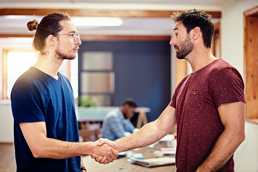 Shot of two men shaking hands together in an office