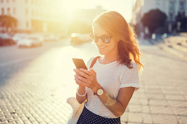 garota sorridente mandando sms lá fora - sun watch - fotografias e filmes do acervo