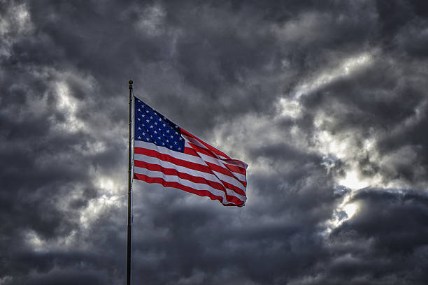istock American flag flapping in dark ominous sky 638778278