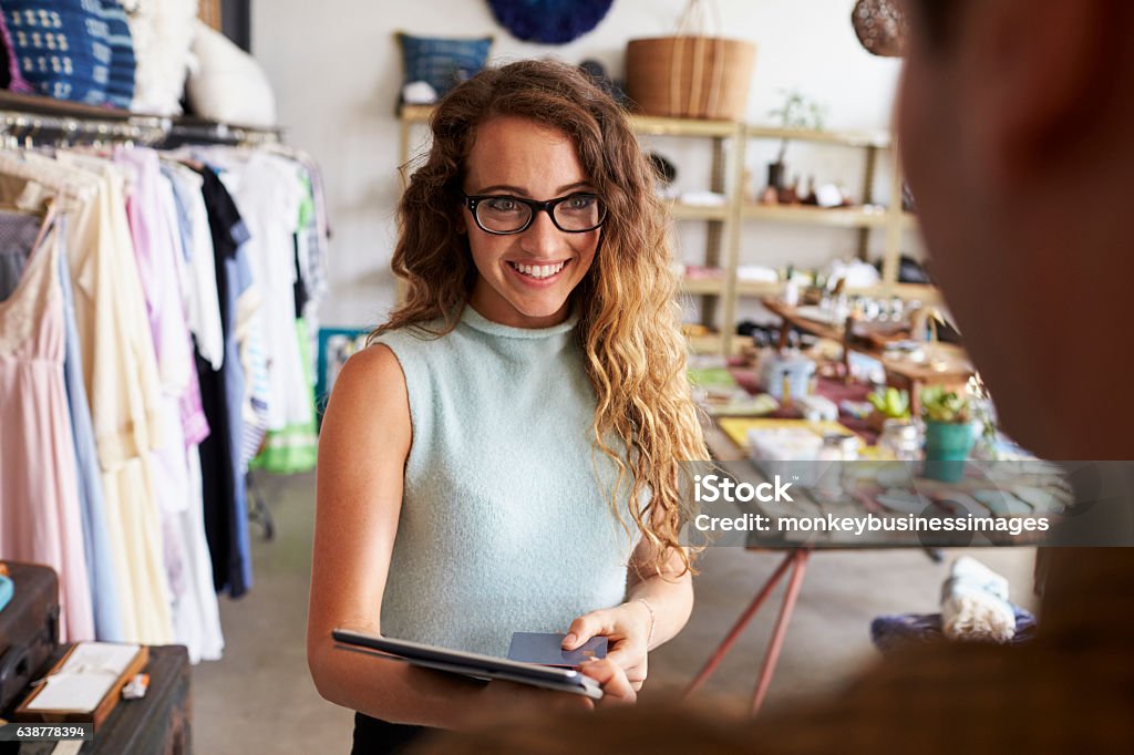 Female boutique manager greeting client in shop Digital Tablet Stock Photo