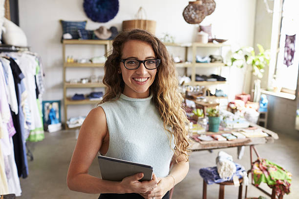 female business owner holding tablet computer in clothes shop - boutique owner store retail occupation imagens e fotografias de stock