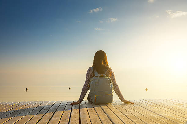 istock Young woman relaxes on lake pier 638780372