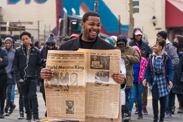 World Mourns King Washington, DC - January 16, 2017: Man holds old newspaper at Martin Luther King, Jr. Day Peace Walk and Parade. martin luther king jr day stock pictures, royalty-free photos & images