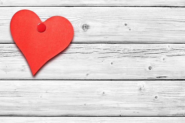 istock Heart shaped note on white weathered wooden wall 638789862