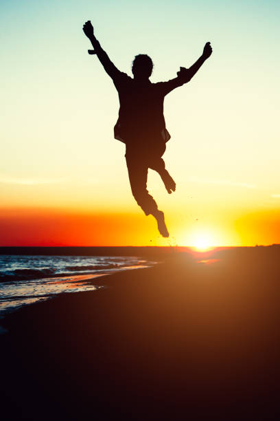 istock Silhouette young woman jumping with hands up on the beach 638789886
