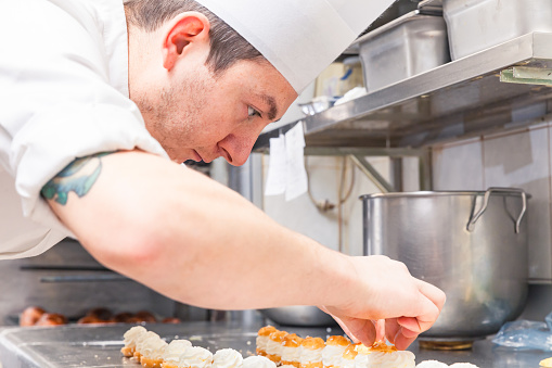 pastry chef assembling small pastries in a commercial kitchen