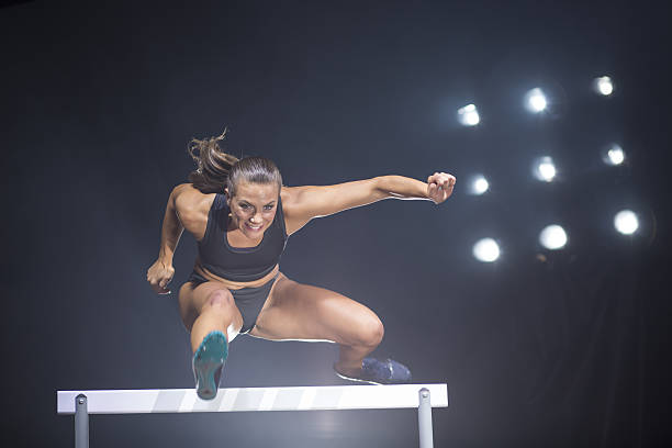 athlete clearing hurdle - hurdling hurdle running track event imagens e fotografias de stock