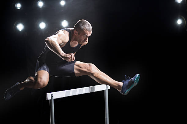 athlete jumping over hurdle - hurdling hurdle running track event imagens e fotografias de stock