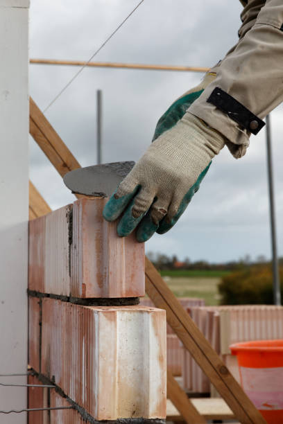 istock close up of bricklayer mason placing a stone outdoors 638796036