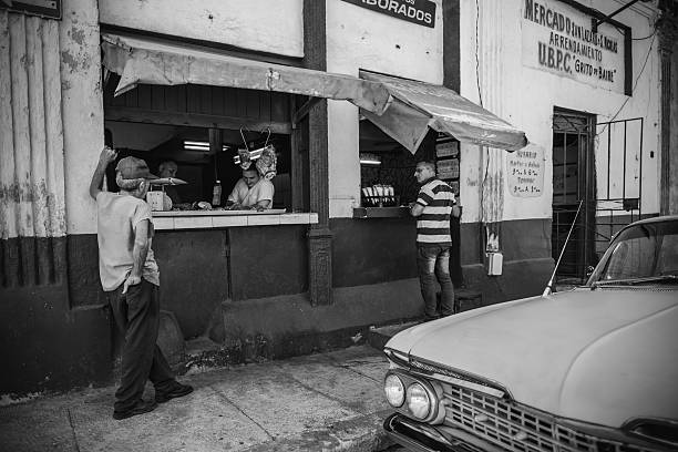 Havana, Cuba- October 8, 2016: Street scene in Old Havana, Cuba. Corner Butcher shop with raw meat on display. Butcher behind the counter. People standing in front of the store, on the sidewalk. Old American car parked on the road. Another work day in Cuban capital.