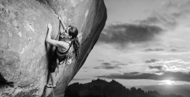 самка альпиниста восхождение большой валун в природе с веревкой - climbing rock climbing women determination стоковые фото и изображения