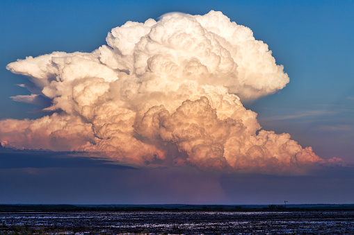 Cumulonimbus clouds fill the sky as a thunderstorm develops at sunset.