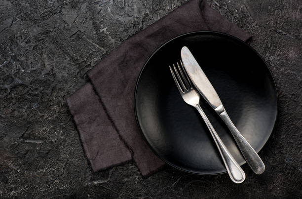 istock Fork, knife with napkin, roses and black plate. On dark 638802604