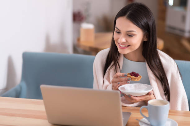istock Cheerful woman using laptop and eating cake in a cafe. 638803210