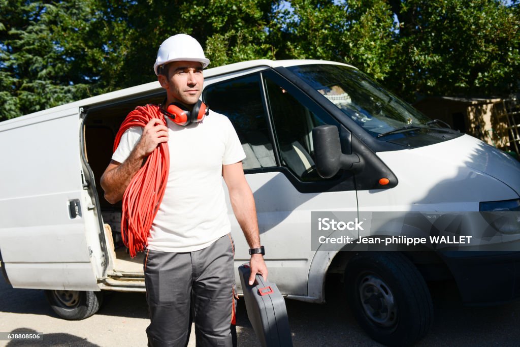 young electrician worker taking tools out of professional truck van young electrician artisan taking tools out of his professional truck van Van - Vehicle Stock Photo