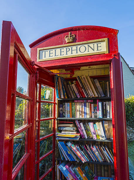 Coombe Bissett, UK - January 18, 2017: An old telephone box with the door open. Inside is now used as a free public library. Lots of books on shelfs, free for people to give and take. Such telephone boxes are found in villages around the UK. This one in Coombe Bissett in Wiltshire. 