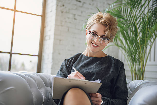 幸せな笑顔の女性は吸収的に書く - clear thinking ストックフォトと画像