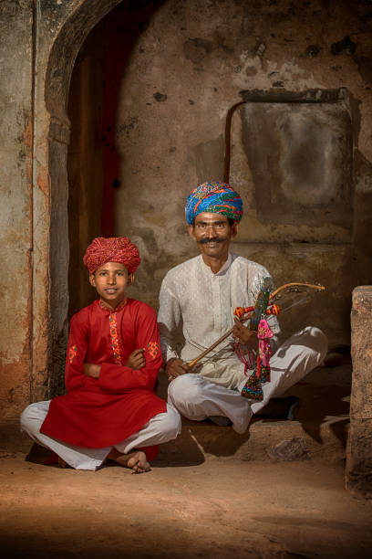 Traditional musicians  from Rajasthan, India Father and son musicians perfoming traditonal  music from Rajasthan with traditional clothing. The man is playing on the typical Rawanhatta music instrument. indian music stock pictures, royalty-free photos & images