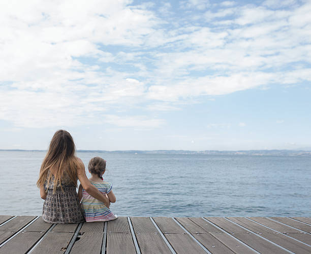 istock Mother and daughter sitting on a landing stage 638820458