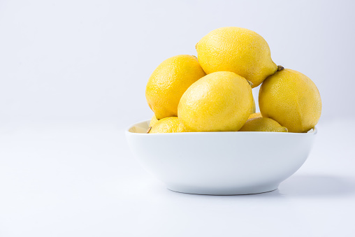 Bowl of Fresh Lemons in a White Bowl on a White Background