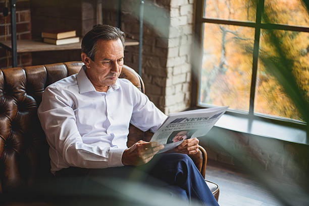 istock Concentrated serious man looking through newspaper 638823034