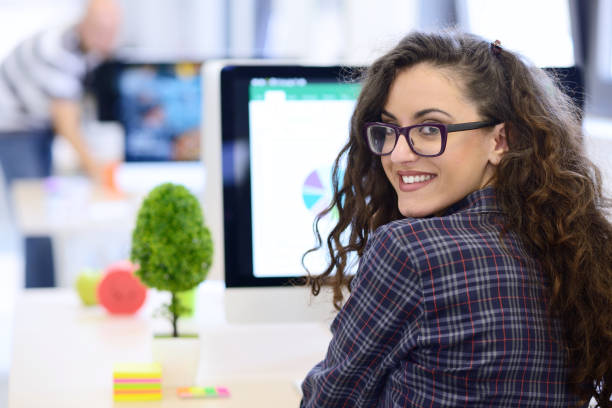 Over the shoulder view of a businesswoman working at computer Over the shoulder view of a businesswoman working at computer and pointing to graph on screen travel agency stock pictures, royalty-free photos & images