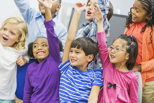 istock Multi-ethnic group of children in class raising hands 638833130