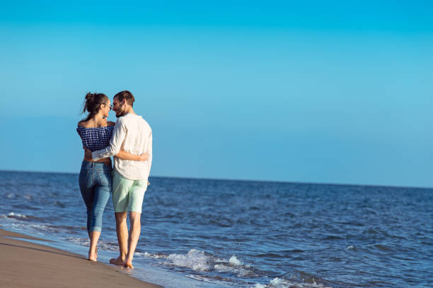 istock Young happy interracial couple walking on beach. 638833164