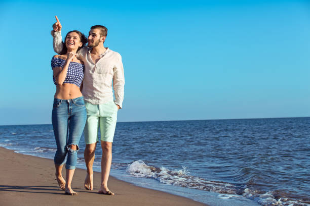 istock Young happy interracial couple walking on beach. 638833552