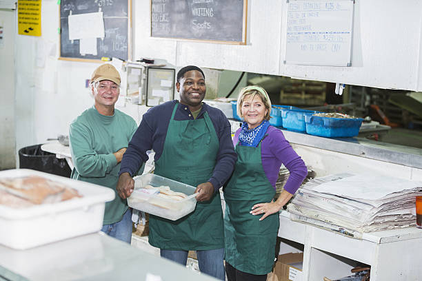 lavoratori multietnici in negozio di pesce - service occupation candid small business carrying foto e immagini stock