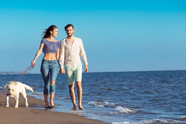 istock two young people running on the beach with dog 638834788