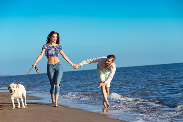 istock two young people running on the beach with dog 638834936