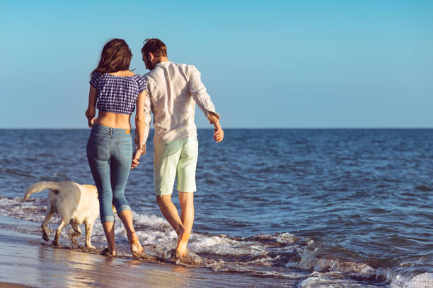 istock two young people running on the beach with dog 638835224