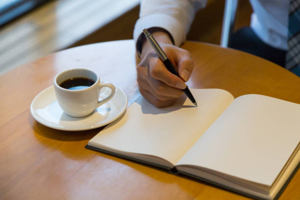 quaderno uomo con penna e caffè su vecchio tavolo di legno - macro book laptop office foto e immagini stock