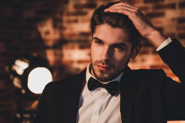 porträt der hübsche junge sexy bräutigam seine haare zu berühren - smoking issues fotos stock-fotos und bilder
