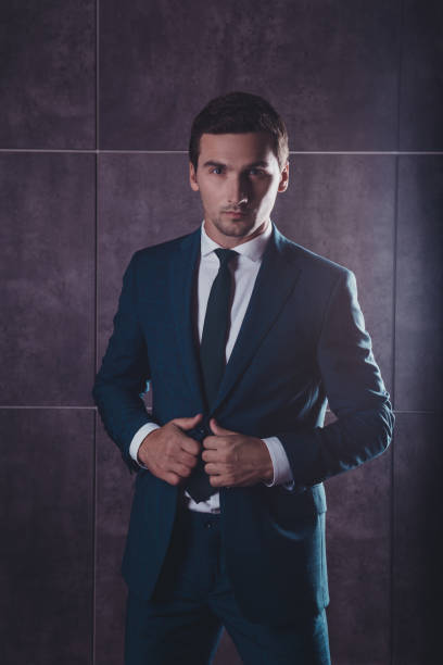 istock brutal handsome man in black suit holding hands on suit 638849436