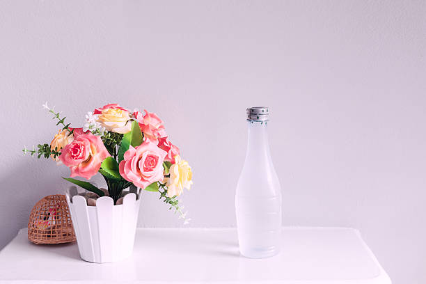flor y botella de agua, sobre mesa blanca - single flower tranquil scene mirror flower fotografías e imágenes de stock