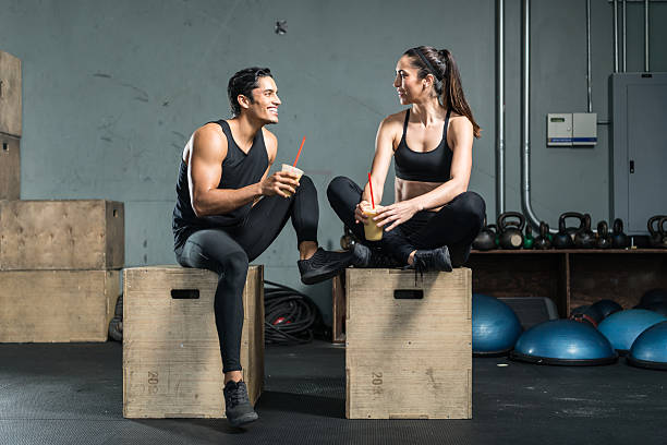 Hispanic Fitness Couple Drinking A Smoothie Hispanic Fitness Couple Drinking A Smoothie couple drinking stock pictures, royalty-free photos & images