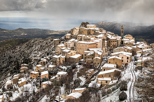 Snow and dark clouds cover the ancient mountain village of Speloncato in the Balagne region of Corsica